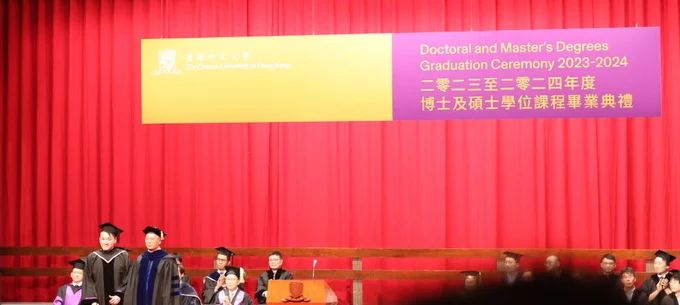 A. Lam and the presenter on stage beneath the CUHK Doctoral and Master’s Degrees Graduation Ceremony 2023–2024 banner