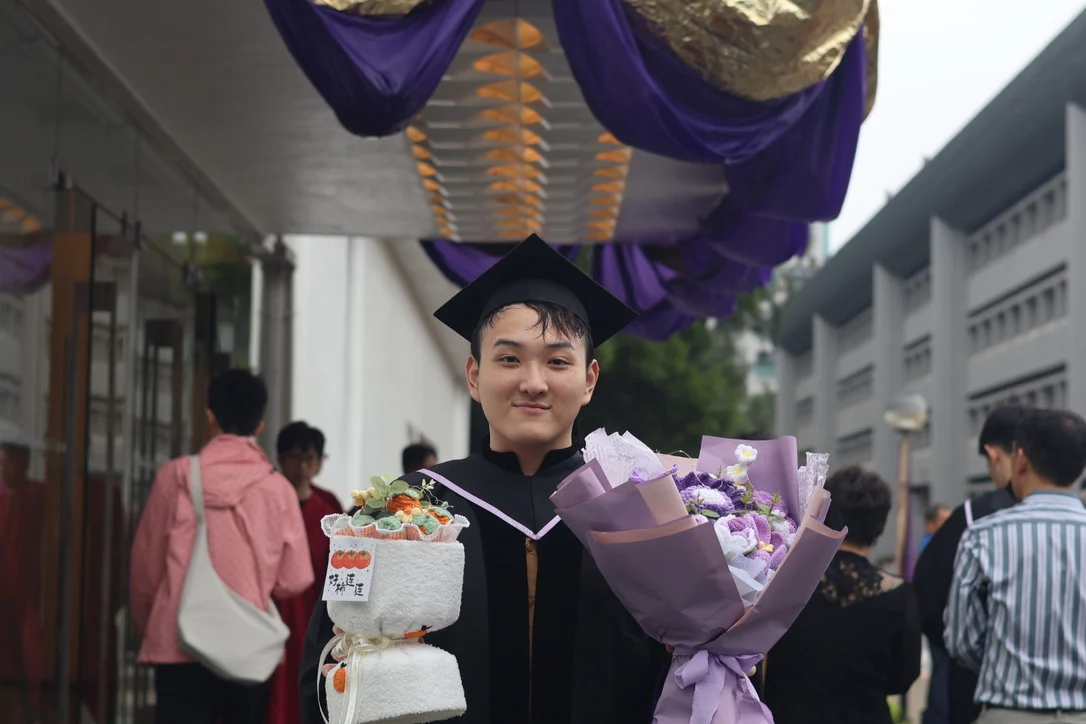 A. Lam at graduation, wearing a mortarboard and a gown with purple trim